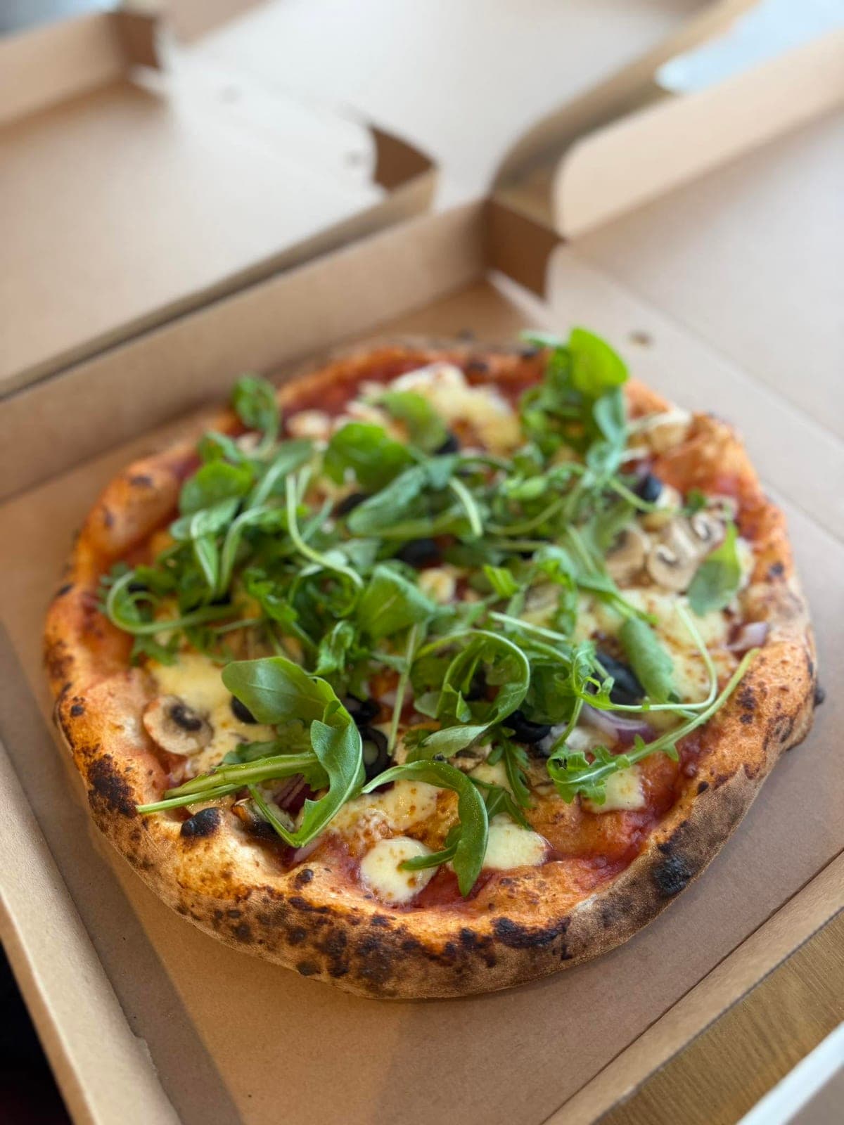 Veggie sourdough pizza with mushrooms, olives, red onion and rocket